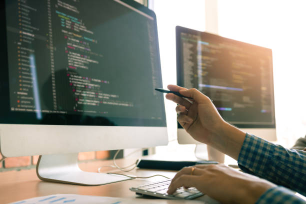 Developing programming working in a software engineers code tech applications on desk in office room.